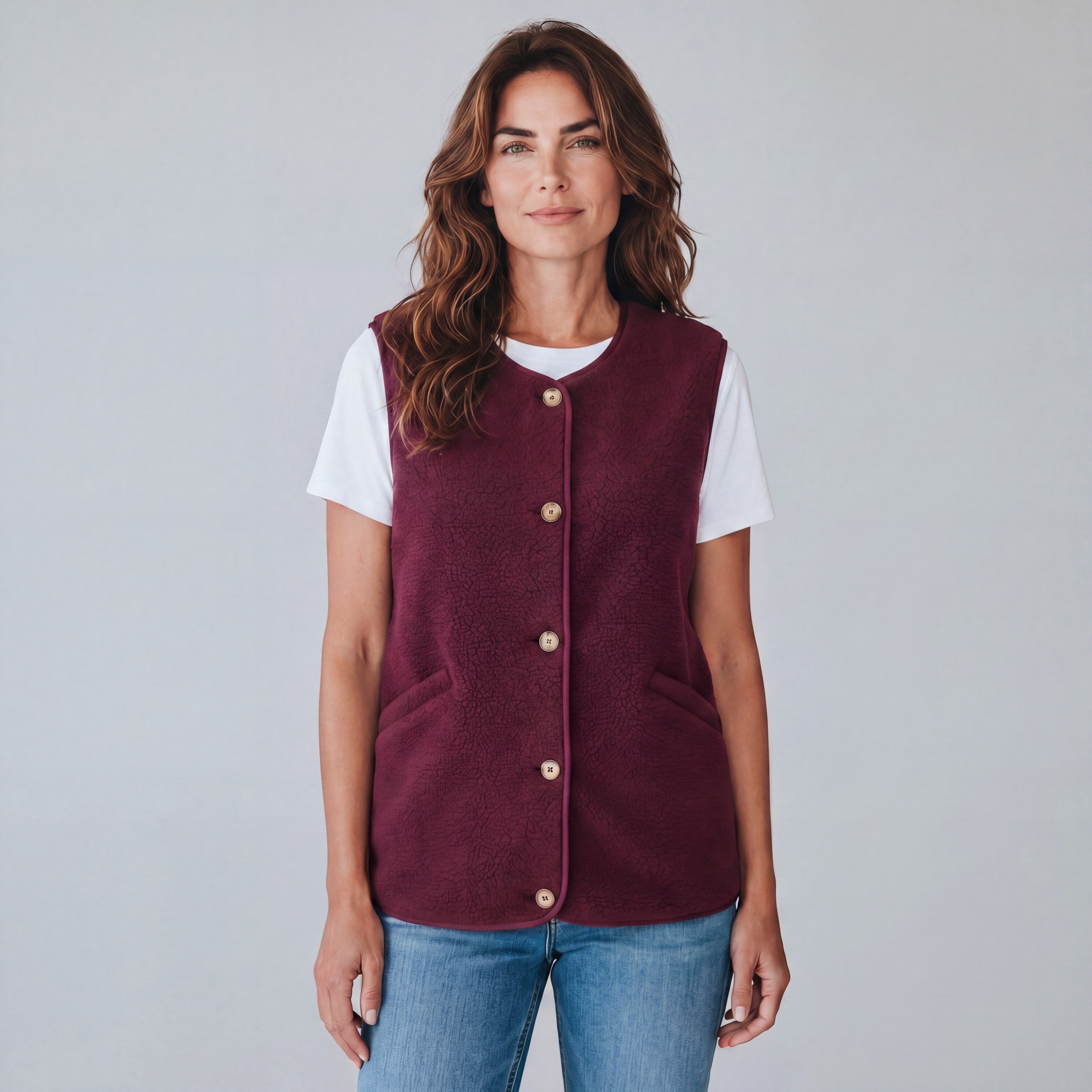 Model draagt een bordeauxrode Bent Merkschoenen Online bodywarmer van fleece met knoopsluiting over een wit T-shirt.